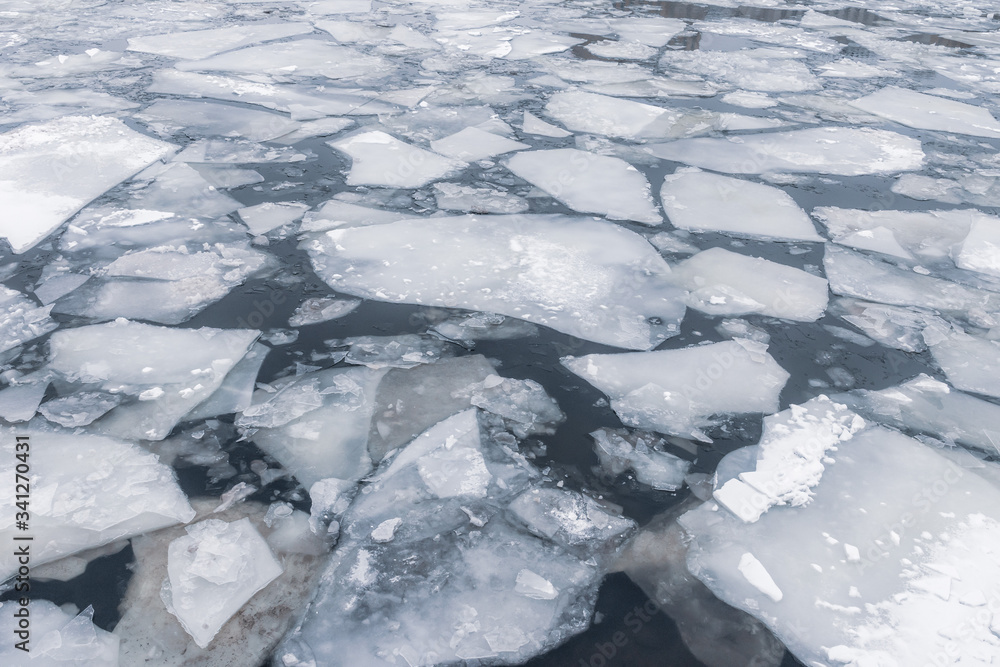 cracked ice on dark river water in spring time