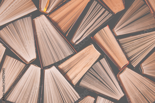 Many old multi-colored open books stand on the bookshelf in the library