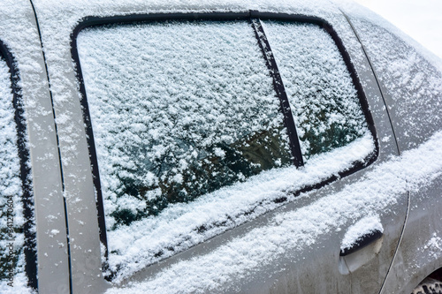 Obraz na płótnie Fragment of a grey car covered with white snow close-up w salonie