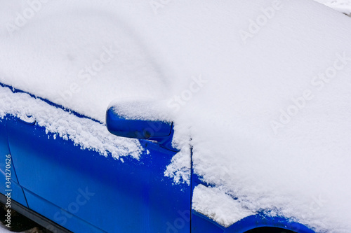 Obraz na płótnie Fragment of a blue car covered with white snow close-up w salonie