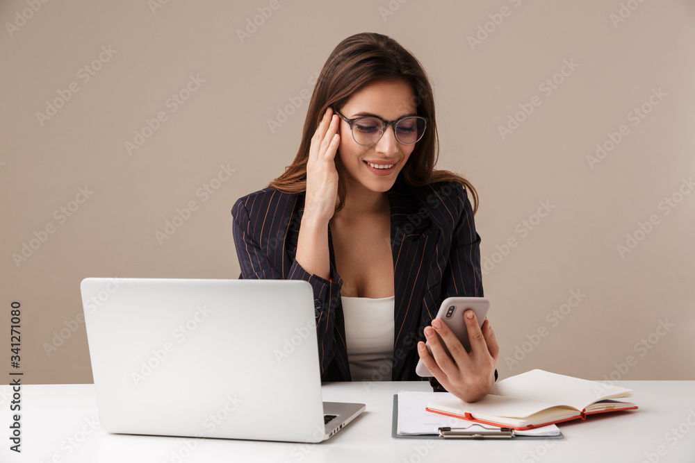 Photo of businesswoman smiling while working with laptop and cellphone Photo of businesswoman smiling while working with laptop and cellphone