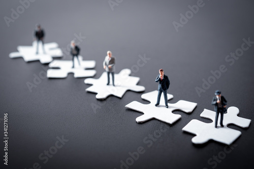 miniature business man thinking about business on jigsaw puzzle