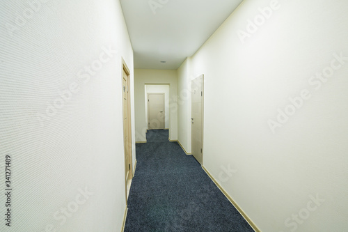 Long bright corridor with doors in a new hotel, hostel