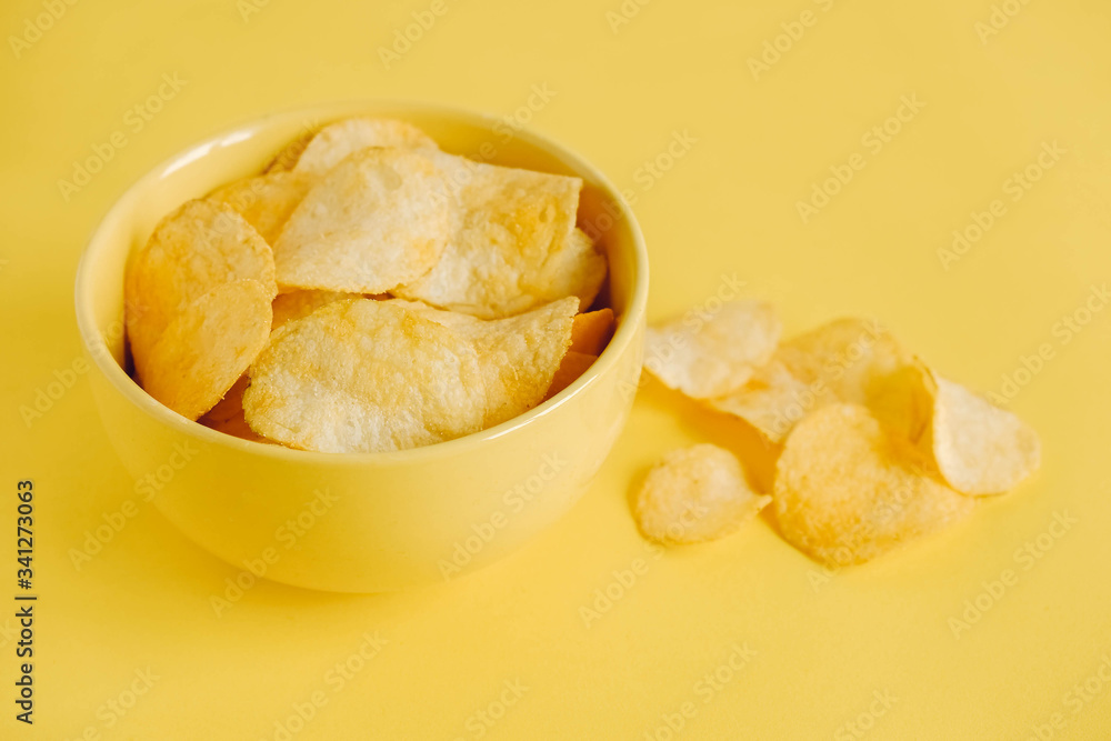 Potato chips in a yellow bowl on a yellow background. Copy, empty space for text