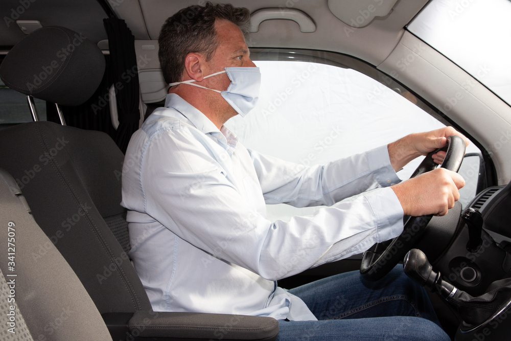 handsome man driving car in protective medical mask handmade during pandemic coronavirus protect driver
