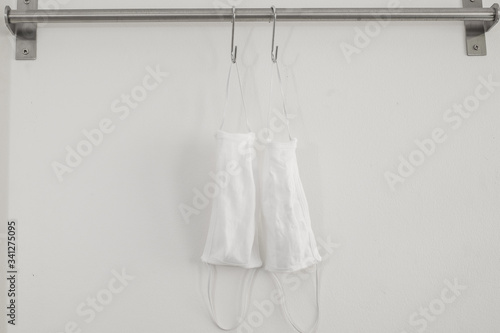 Two cotton cloth masks or hygiene masks are hanging on clothes hooks. Prevention covid-19 virus infection, Healthcare concept