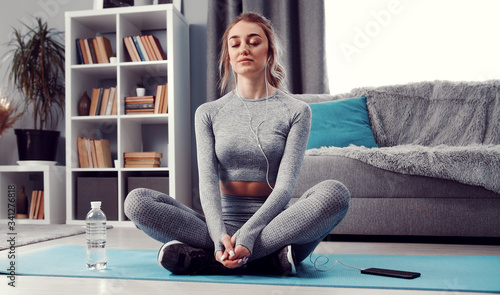Foto Meditative lady with closed eyes sitting with folded legs on exercise mat on flo