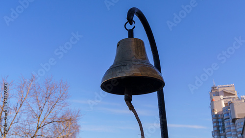 Old skool bronze fire bell on the classic blue sky background. Alarm fire concept.