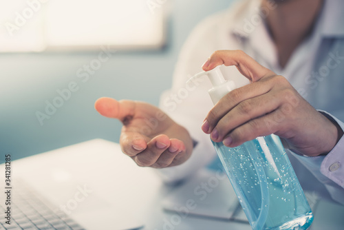 Business girl washing his hands with an alcohol gel in a pump-like bottle to prevent the spread of the Covid-19 virus.