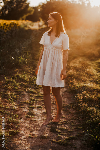 Young beautiful girl on the sunflowers field posing in the  white dress