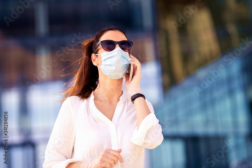 Close-up portrait of casual businesswoman wearing face mask in the city while giving a call