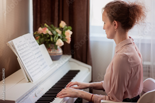 Young beautiful woman is playing piano at home. Music concept