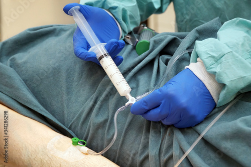 Arzt in OP hält spritzt einem Patienten Narkosemittel oder Sedativum