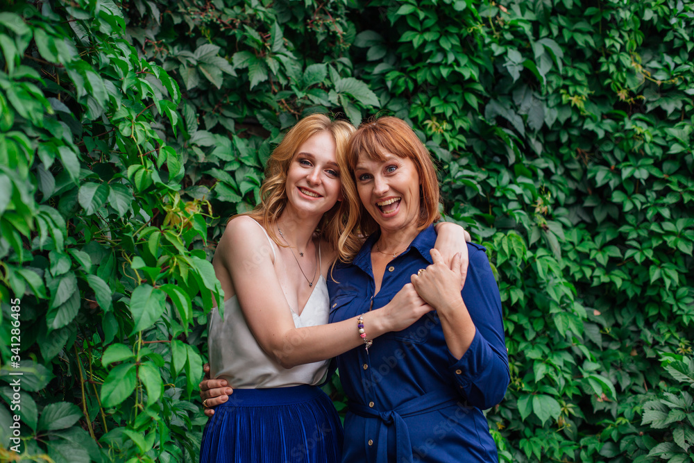 Beautiful mother and her grown up daughter hugging each other and laughing on a summer day outside Beautiful mother and her grown up daughter hugging each other and laughing on a summer day outside