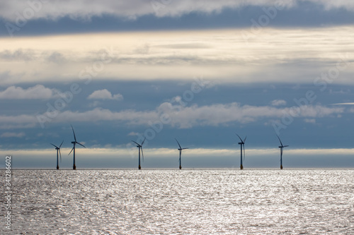 Offshore wind farm turbines on sea horizon with cloudscape background. © Ian Dyball