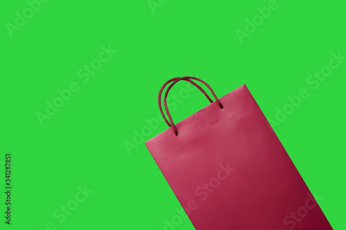 Red paper shopping bag isolated on green background