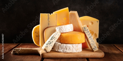 Cheese panorama, many different types of cheeses, a side view on a dark background photo