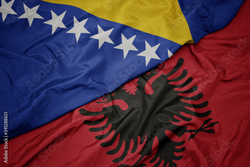 Valokuva waving colorful flag of albania and national flag of bosnia and herzegovina