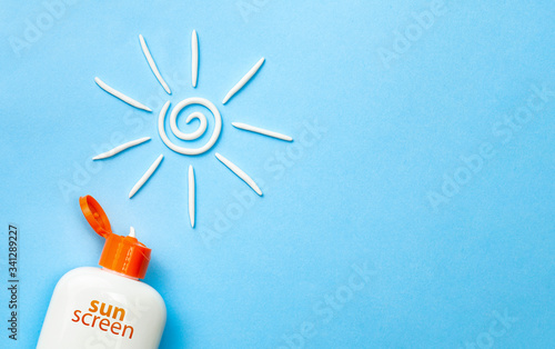 Sunscreen. Cream in the form of sun on blue background with white tube. Copy space for text photo