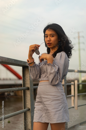 A young beautiful girl poses on an old bridge.