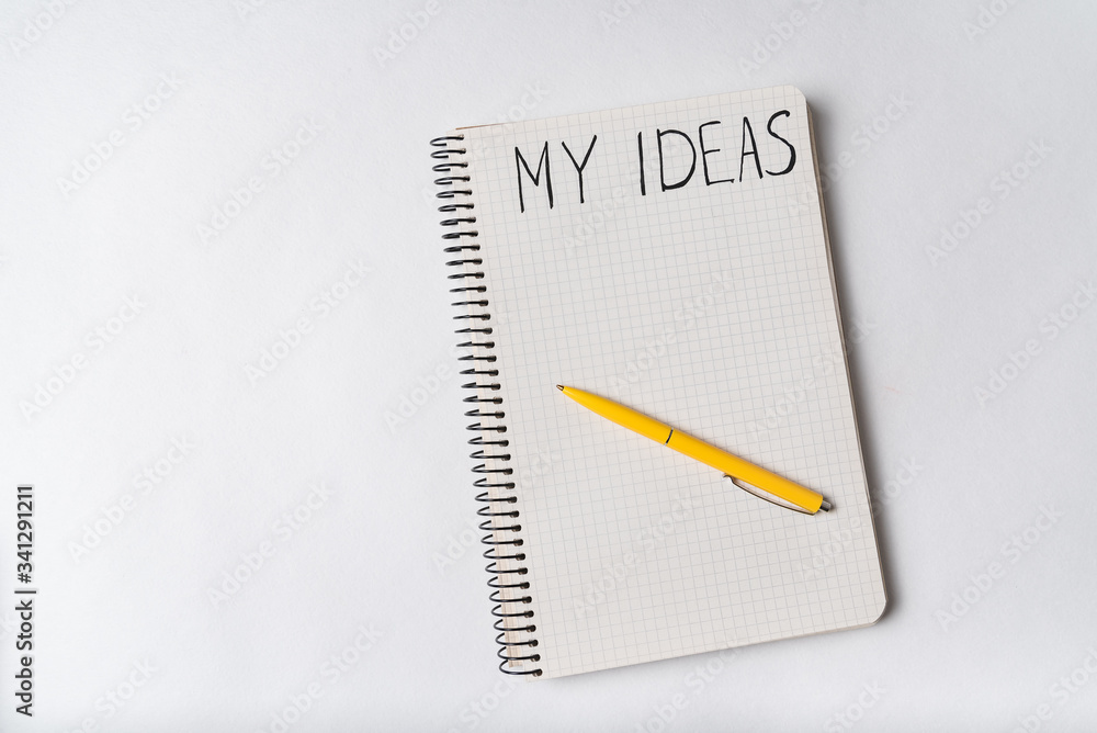 Notepad with words MY IDEAS on white background. Top view, pen on notebook Notepad with words MY IDEAS on white background. Top view, pen on notebook
