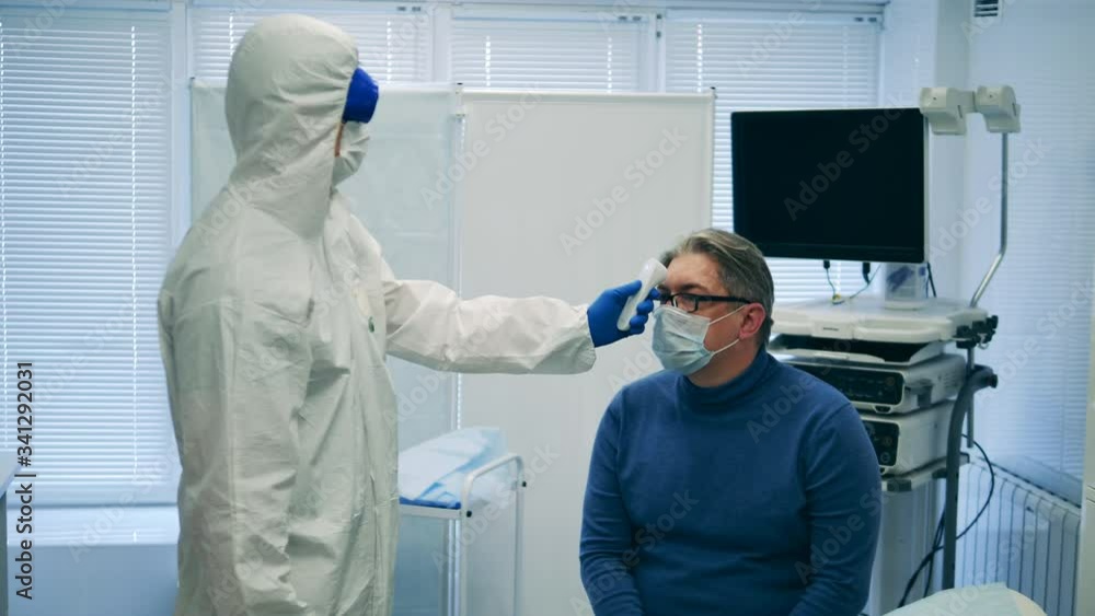 Doctor is checking patient's temperature with an infrared thermometer Doctor is checking patient's temperature with an infrared thermometer