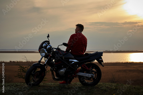  young man with a motorcycle at sunset