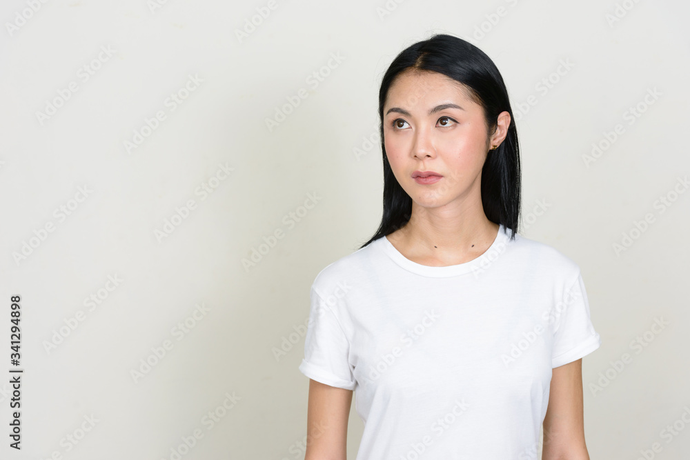 Portrait of young beautiful Asian woman thinking and looking up Portrait of young beautiful Asian woman thinking and looking up