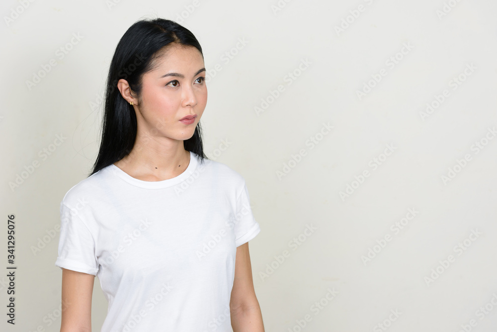 Portrait of young beautiful Asian woman thinking and looking up Portrait of young beautiful Asian woman thinking and looking up