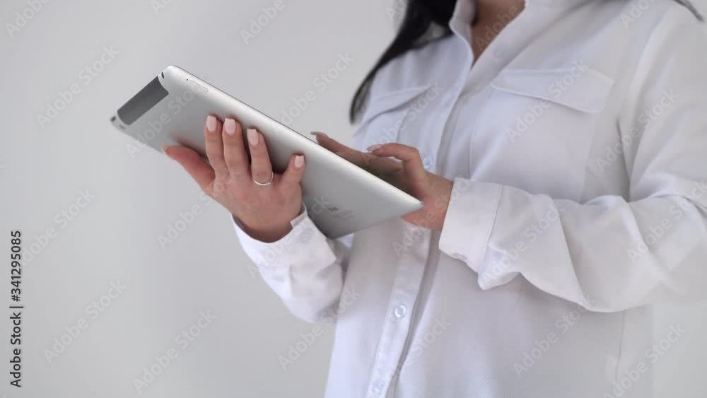 A woman's hands are typing on a digital tablet. Close up of a girl's hands typing a message on an electronic tablet A woman's hands are typing on a digital tablet. Close up of a girl's hands typing a message on an electronic tablet