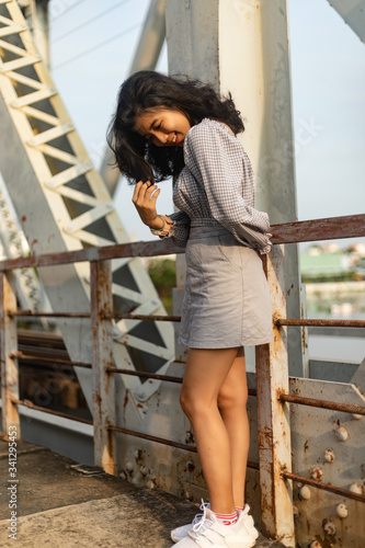 A young beautiful girl poses on an old bridge.
