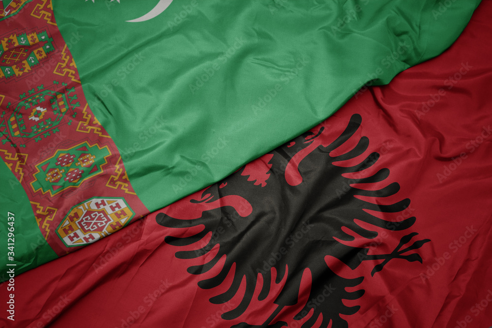waving colorful flag of albania and national flag of turkmenistan.