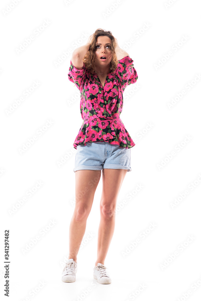 Shocked frustrated young woman with hands on head looking up having headache pain. Full body isolated on white background. Shocked frustrated young woman with hands on head looking up having headache pain. Full body isolated on white background.