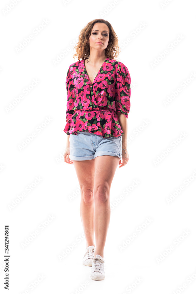 Confident elegant young pretty woman in floral summer short walking and looking at camera. Full body isolated on white background. Confident elegant young pretty woman in floral summer short walking and looking at camera. Full body isolated on white background.