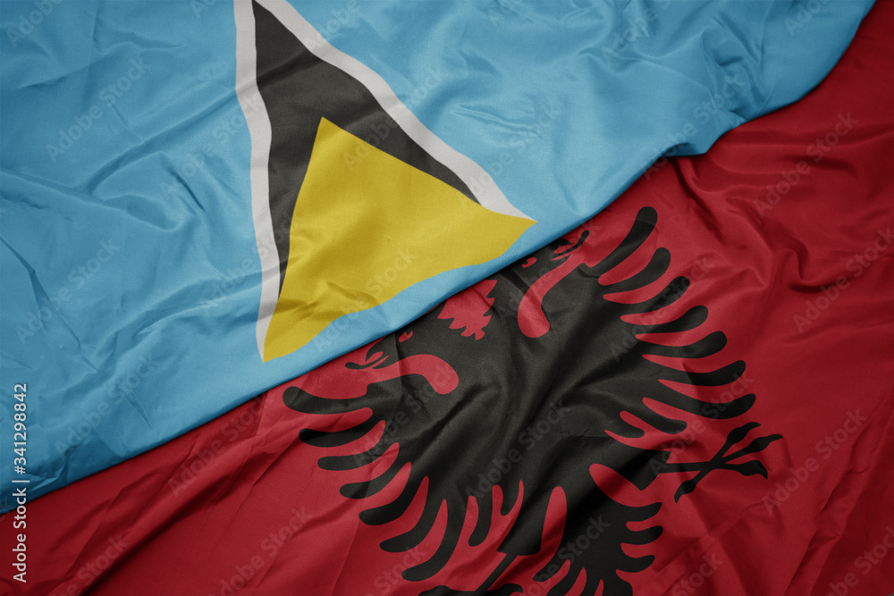 waving colorful flag of albania and national flag of saint lucia.