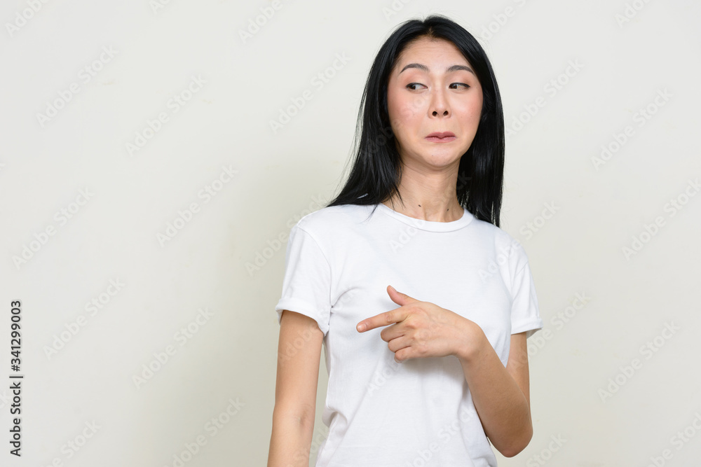 Portrait of young Asian woman gossiping while pointing finger Portrait of young Asian woman gossiping while pointing finger
