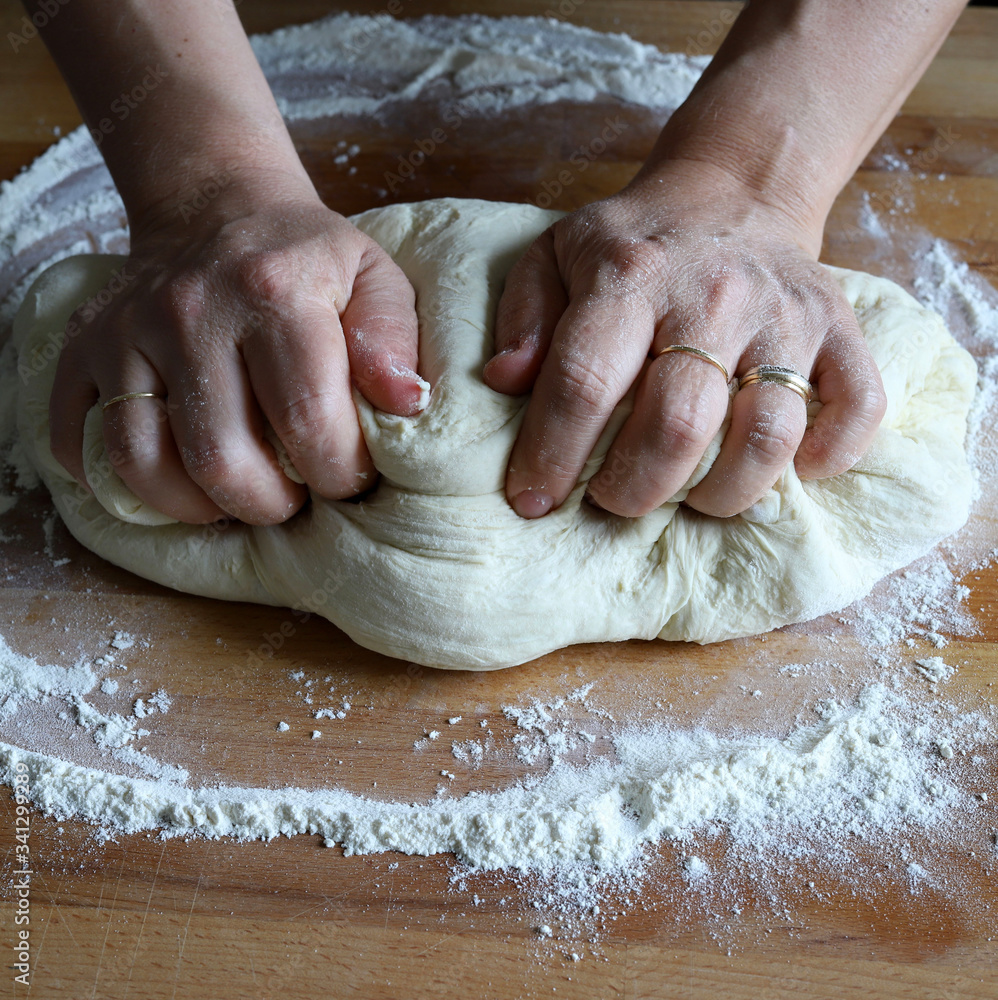 Concetto di cucina. Mani femminili che preparano la pasta fresca fatta in casa della pizza su un tavolo di legno infarinato. Avvicinamento. Cucina italiana.