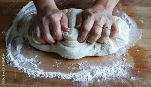Concetto di cucina. Mani femminili che preparano la pasta fresca fatta in casa della pizza su un tavolo di legno infarinato. Avvicinamento. Cucina italiana.