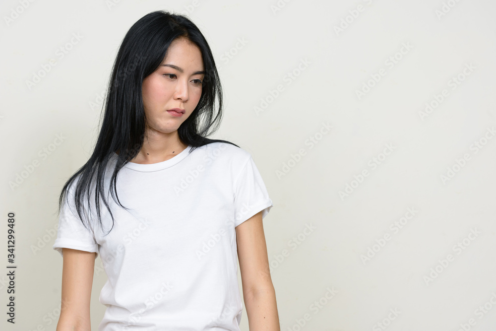 Portrait of stressed young Asian woman thinking and looking down Portrait of stressed young Asian woman thinking and looking down