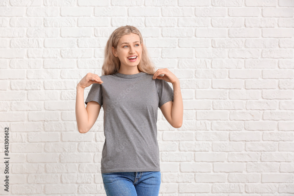 Woman in stylish t-shirt on white brick background Woman in stylish t-shirt on white brick background