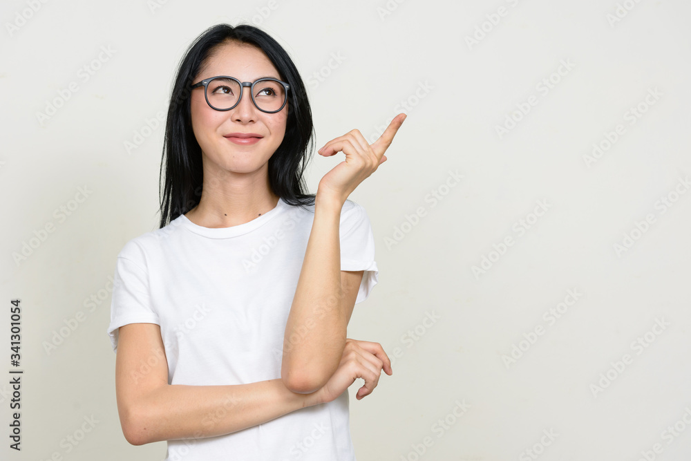 Young beautiful Asian nerd woman thinking and pointing up Young beautiful Asian nerd woman thinking and pointing up