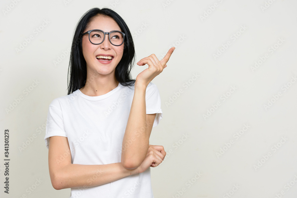 Happy young beautiful Asian nerd woman pointing up and having idea Happy young beautiful Asian nerd woman pointing up and having idea