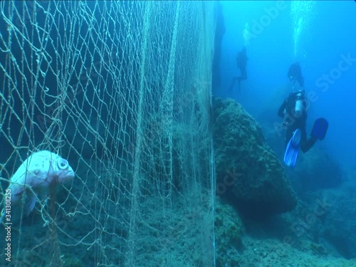 fish net underwater scuba divers getting close dangerous ghost nets ocean scenery
 photo
