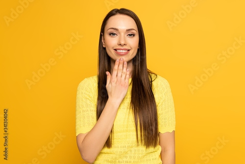 Smiling woman showing word speak in deaf and dumb language on yellow background