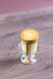 spill Dalgona coffee in glass cup on brown wooden background 