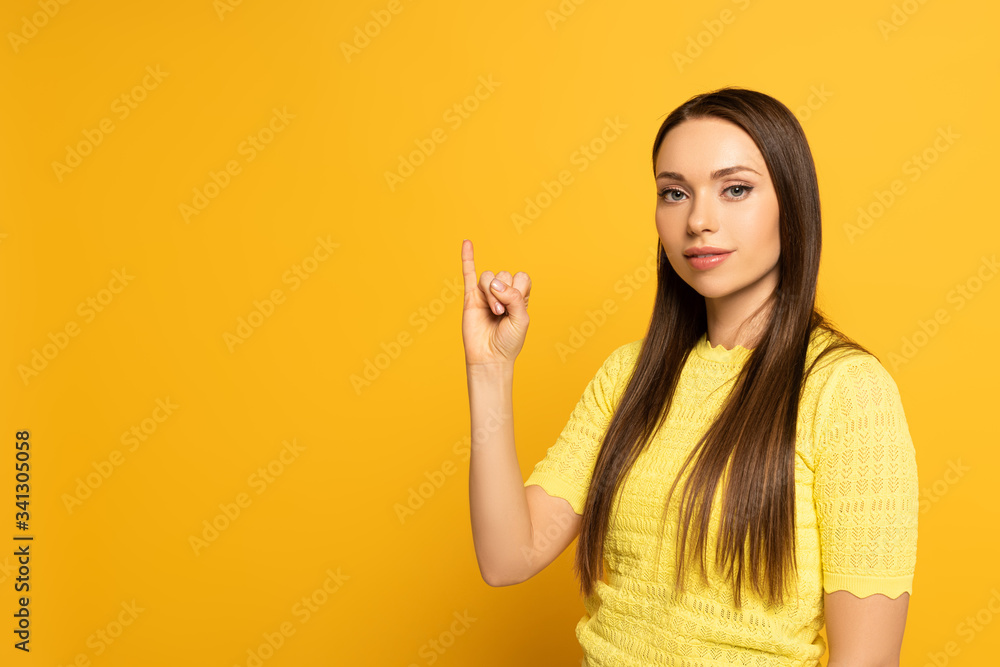 Beautiful woman showing letter from sign language on yellow background Beautiful woman showing letter from sign language on yellow background