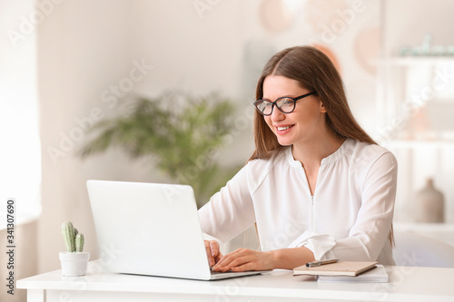 Portrait of beautiful young businesswoman working on laptop in office