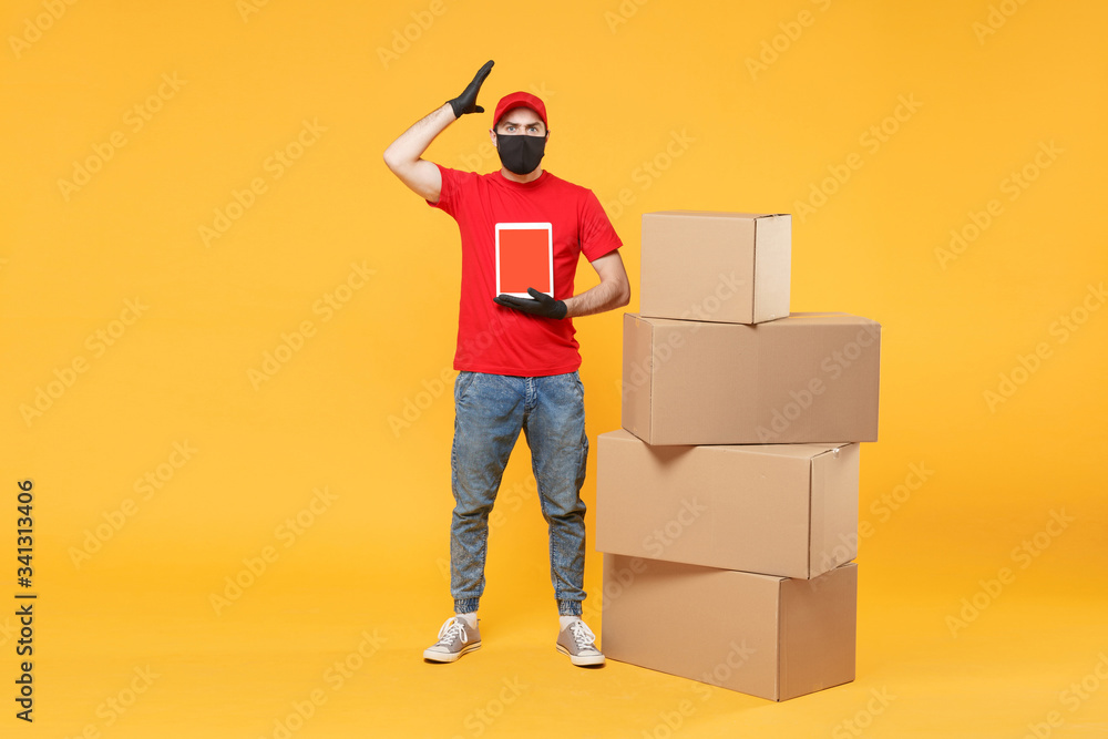 Delivery man employee in red cap blank t-shirt uniform face mask glove hold empty cardboard box isolated on yellow background studio Service quarantine pandemic coronavirus flu virus 2019-ncov concept Delivery man employee in red cap blank t-shirt uniform face mask glove hold empty cardboard box isolated on yellow background studio Service quarantine pandemic coronavirus flu virus 2019-ncov concept