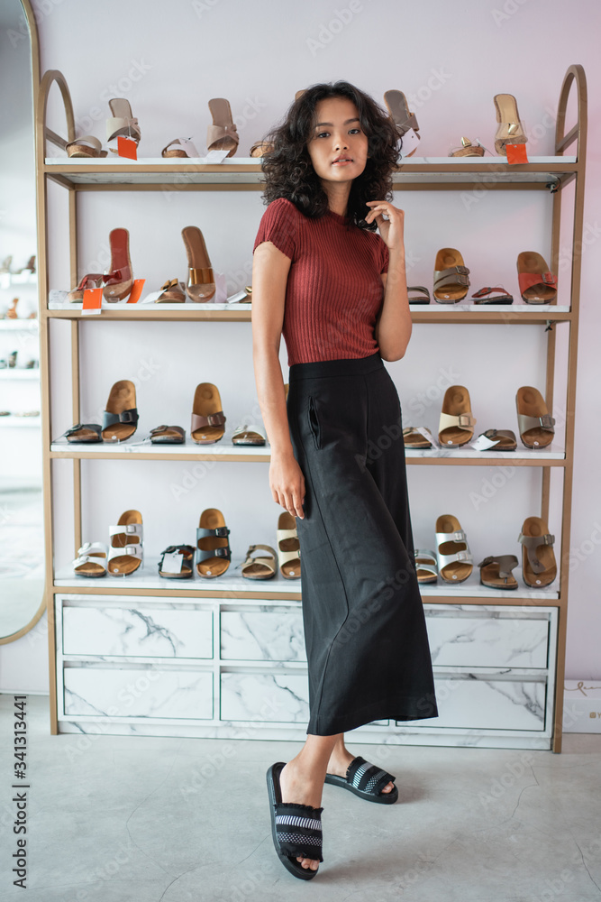 asian woman posing in front of shoes shelves in the boutique shopping store