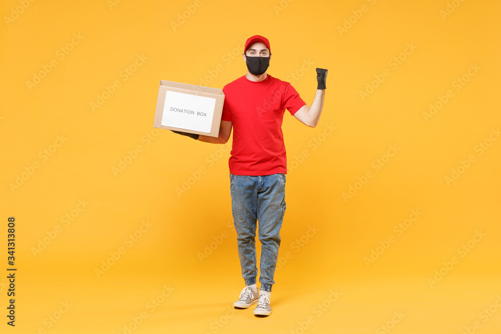 Delivery man employee in red cap blank t-shirt uniform face mask glove hold donations cardboard box isolated on yellow background studio Service quarantine pandemic coronavirus virus 2019-ncov concept Delivery man employee in red cap blank t-shirt uniform face mask glove hold donations cardboard box isolated on yellow background studio Service quarantine pandemic coronavirus virus 2019-ncov concept